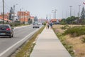 View of pedestrian path with people, persons walking on path close to the street with cars