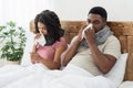 Ill african american couple wrapped in scarfs sitting in bed Royalty Free Stock Photo