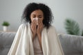 Ill african woman covered with blanket blowing nose got flu Royalty Free Stock Photo