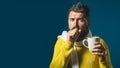 Ill bearded man with flu or fever coughing and drinking healing tea. Unwell man coughing into his fist. Sick man in Royalty Free Stock Photo
