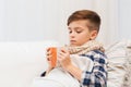 Ill boy with flu in scarf drinking tea at home Royalty Free Stock Photo