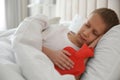 Ill boy with hot water bottle suffering from cold in bed at home Royalty Free Stock Photo