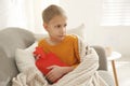 Ill boy with hot water bottle suffering from cold at home Royalty Free Stock Photo