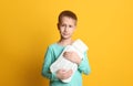 Ill boy with hot water bottle suffering from cold on yellow background Royalty Free Stock Photo