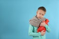 Ill boy with hot water bottle suffering from cold on light blue background, space for text Royalty Free Stock Photo