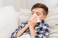 Ill boy lying in bed and blowing his nose at home Royalty Free Stock Photo