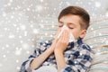 Ill boy lying in bed and blowing his nose at home Royalty Free Stock Photo