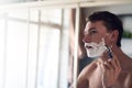 Ill face the day with a smooth face. a young man shaving his beard while looking at himself in the mirror. Royalty Free Stock Photo