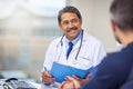 Ill fix you right up. a cheerful mature male doctor seated at his desk while consulting a patient inside a hospital Royalty Free Stock Photo