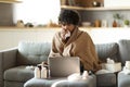 Ill indian man covered in blanket looking at laptop and sneezing nose Royalty Free Stock Photo