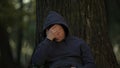 Ill man touching head, sitting under tree in park, sudden migraine attack insult