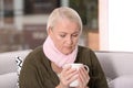 Ill mature woman with cup of hot tea for cough on sofa Royalty Free Stock Photo