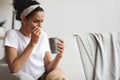 Ill millenial lady holding mug and cleaning nose with napkin Royalty Free Stock Photo