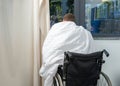 Ill patient sitting by the window on wheelchair covered with quilt in hospital ward Royalty Free Stock Photo