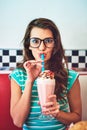 Ill risk the brain freeze. Cropped portrait of an attractive young woman enjoying a milkshake in a retro diner.