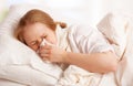 Ill sick young woman sneezes into a handkerchief in bed