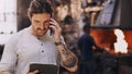 Ill submit my order online. a young man talking on his cellphone while using a digital tablet in his workshop. Royalty Free Stock Photo