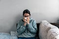 Ill upset young woman sitting on sofa covered with blanket freezing blowing running nose got fever caught cold sneezing in tissue Royalty Free Stock Photo