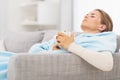 Ill woman with cup of hot beverage sitting on couch Royalty Free Stock Photo