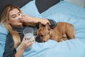 Sick female lying in bed with her sad dog Royalty Free Stock Photo