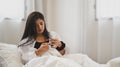 An ill woman is holding a glass of water after consuming a pill at the bed Royalty Free Stock Photo