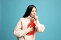 Ill woman with hot water bottle coughing on light blue background Royalty Free Stock Photo