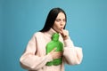 Ill woman with hot water bottle coughing on light blue background Royalty Free Stock Photo