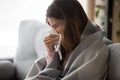 Ill young woman covered with blanket blowing nose got flu Royalty Free Stock Photo