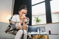 Ill young woman sit on sofa covered with blanket, freezing, blowing her runny nose, sneeze in tissue. Female got fever Royalty Free Stock Photo