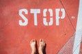 An illegal immigrant stands barefoot at a stop sign on the ground Royalty Free Stock Photo