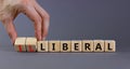 Illiberal or liberal symbol. Businessman turns wooden cubes and changes the word illiberal to liberal. Beautiful grey background. Royalty Free Stock Photo