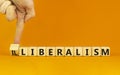 Illiberalism or liberalism symbol. Businessman turns a cube and changes the word `illiberalism` to `liberalism`. Beautiful ora