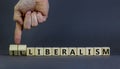 Illiberalism or liberalism symbol. Businessman turns cubes and changes the word `illiberalism` to `liberalism`. Beautiful grey