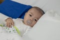 Illness asian baby boy lying down on sickbed and looking at camera Royalty Free Stock Photo