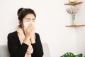 Illness Asian woman sneezing hand holding tissue paper covering her runny nose Royalty Free Stock Photo