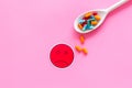 Illness. Drug intake. Pills in spoon near sad face emoji on pink background top view space for text