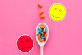 Illness. Drug intake. Pills in spoon near sad face emoji on pink background top view space for text