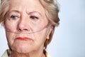 Illness and regret. Closeup of a sickly senior woman wearing a nasal cannula for oxygen isolated on blue - Copyspace. Royalty Free Stock Photo