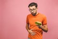 Illness sad young man in casual put hand on pain abdomen, stomach-ache, standing and holding burger isolated on pinke background. Royalty Free Stock Photo