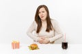 Illness woman put hands on pain abdomen, stomach-ache at table with burger, french fries, cola in glass bottle isolated