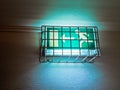 illuminanted exit sighn behind a protected metal cage Royalty Free Stock Photo