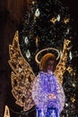 Illuminated angel in front of a Christmas tree