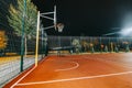 Illuminated basketball playground with red pavement, modern new basketball net Royalty Free Stock Photo