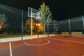 Illuminated basketball playground with red pavement, modern new basketball net Royalty Free Stock Photo