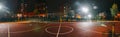 Illuminated basketball playground with red pavement, modern new basketball net Royalty Free Stock Photo