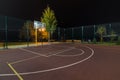 Illuminated basketball playground with red pavement, modern new basketball net Royalty Free Stock Photo