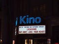 Illuminated billboard above cinema closed due to Covid-19 lockdown in city center with slogan.