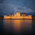 Illuminated Budapest parliament building at night with dark sky and reflection in Danube river