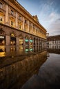 Illuminated building with a reflection in the still water at night in Milan