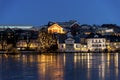 Illuminated buildings and light decorated trees on the shore of Stavanger city lake at night